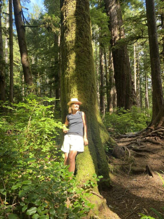 woman leans on the trunk of a green tree